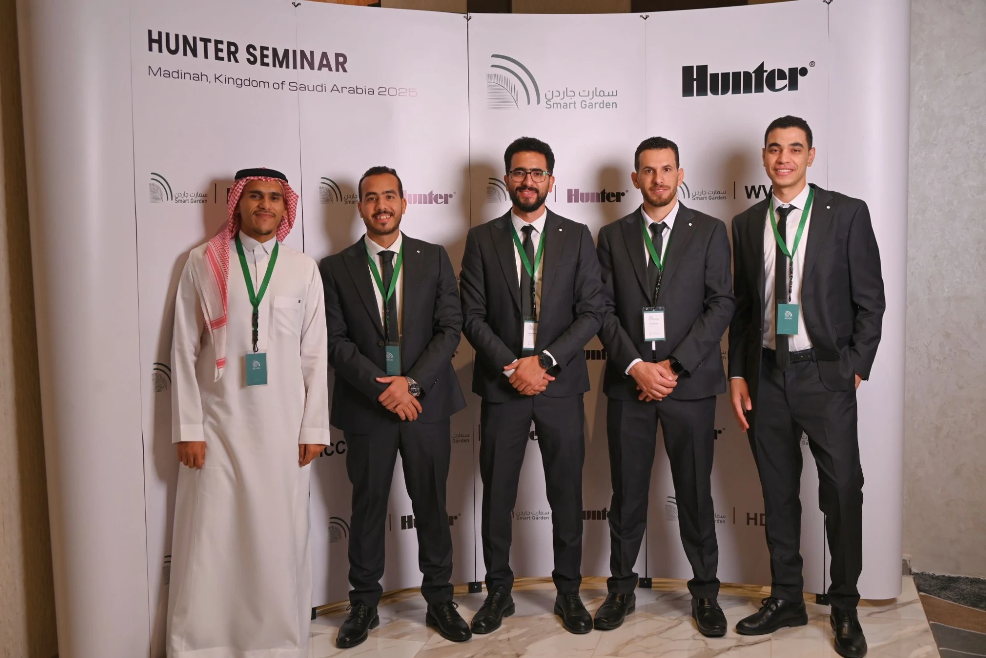 فريق الحديقة الذكية أمام جدار الندوة، ويحمل الجدار عنوان ندوة Hunter بالمدينة المنورة وشعاري الحديقة الذكية وHunter.